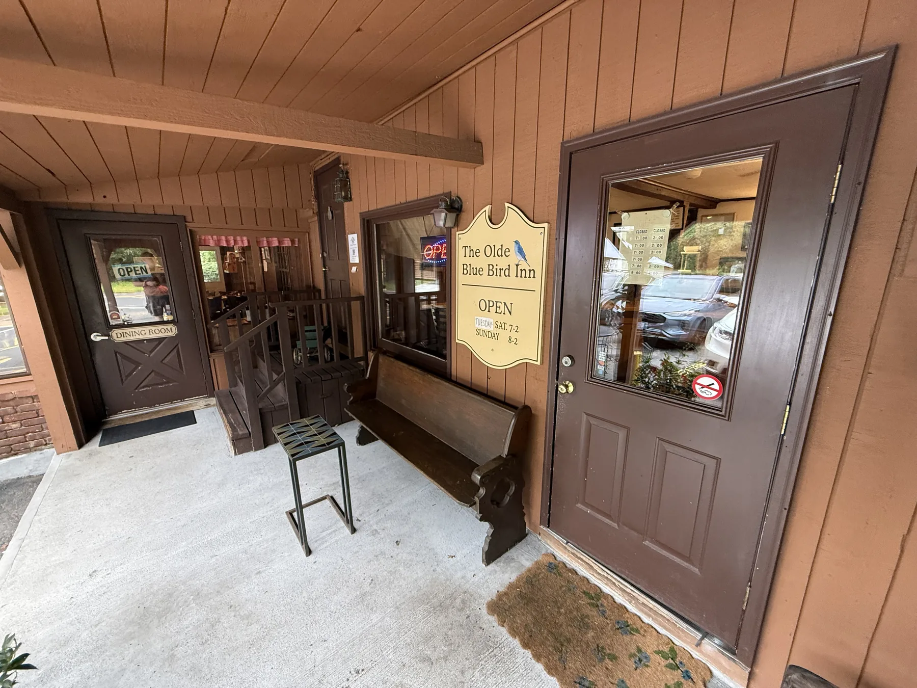 The covered entrance: a door marked Dining Room on the left and the main door on the right, beside the hanging Olde Blue Bird Inn sign