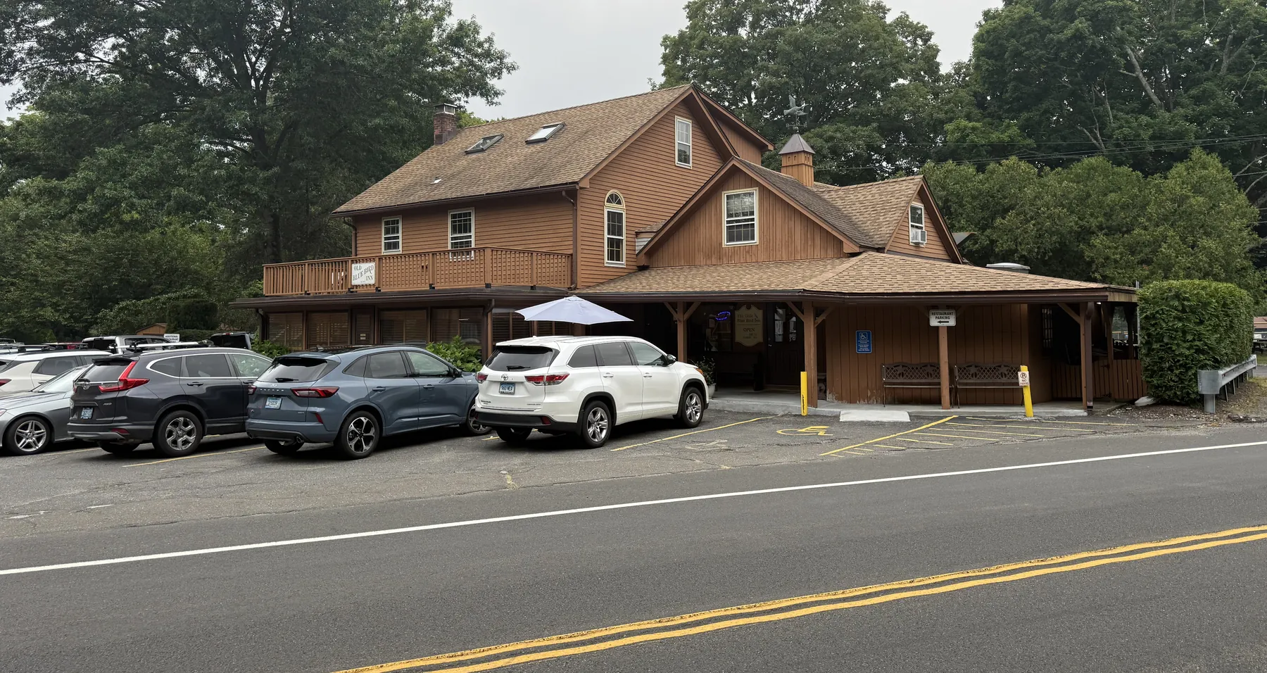 The Olde Blue Bird Inn seen from Black Rock Turnpike, a brown clapboard building set back behind a parking lot